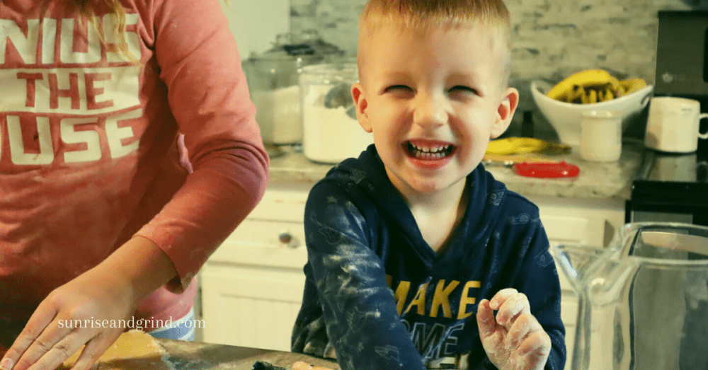 little boy smiling as he makes cookies