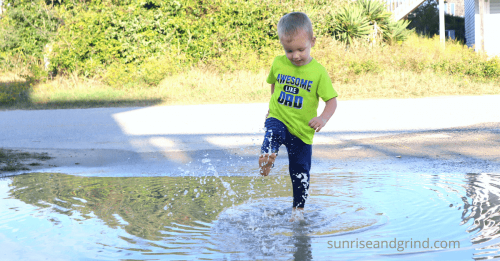 little boy splashing in a puddle