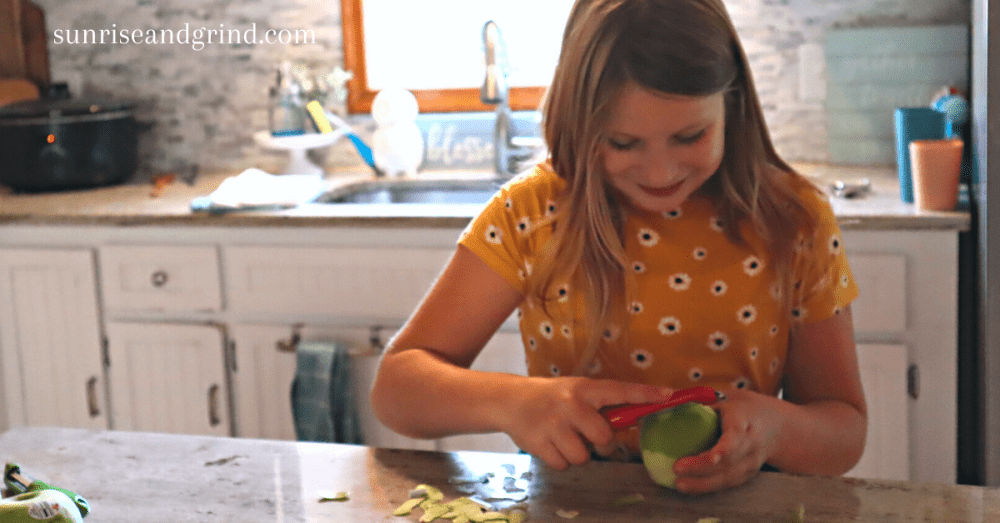 little girl peeling apples at the counter