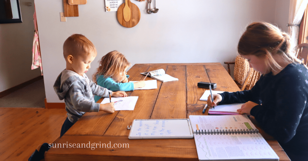 kids sitting at a farmhouse table doing homeschool