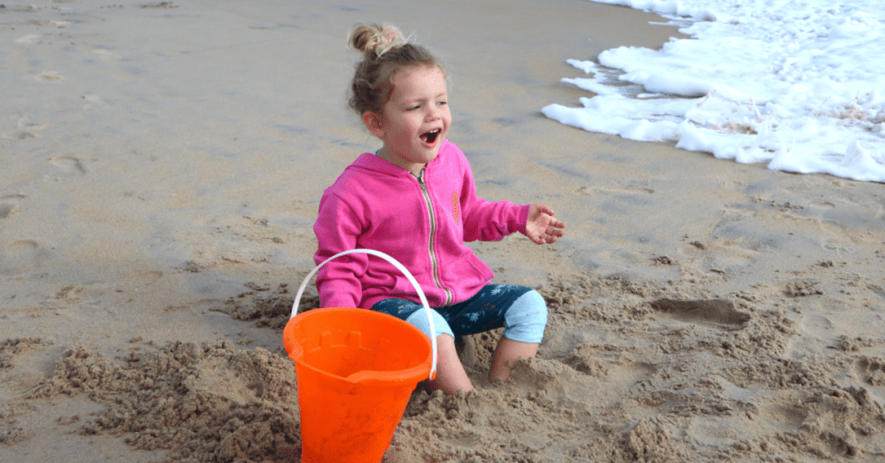 little girl happily playing in the sand